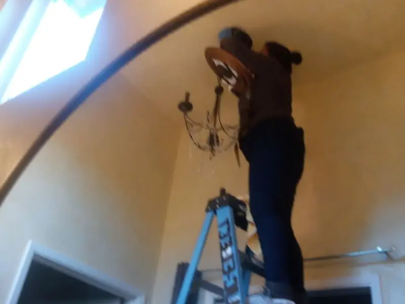 Electrician installing a chandelier in a Louisville residence